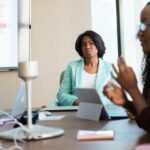 selective focus photography of woman in gray blazer looking at woman in black top