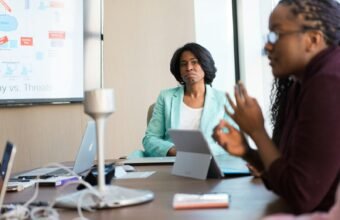 selective focus photography of woman in gray blazer looking at woman in black top